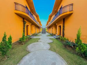 a walkway between two orange buildings with trees at Spree Resort Jim Corbett in Belparāo