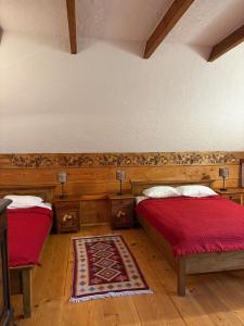 a bedroom with two beds with red sheets and a rug at Hriady in Wetlina
