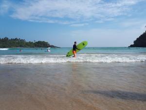 Cactus reef في آهانغاما: شخص يحمل لوح ركوب الأمواج على الشاطئ +3 صور
