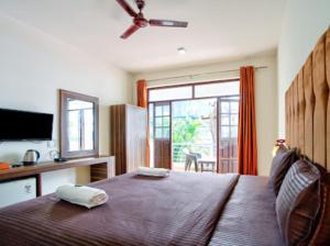 a bedroom with a large bed with a large window at Hotel Sky Blue Baga Goa in Baga