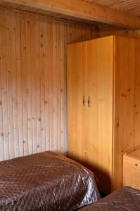 ヤブルニツァにあるСадиба "Альпійській дворик"の木製の壁のベッドルーム1室、ベッド1台、キャビネットが備わります。