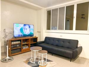 a living room with a black couch and a tv at EC HomeStay in Tarlac
