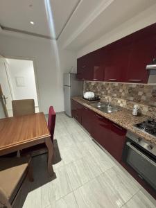 a kitchen with red cabinets and a wooden table at Résidence Maha in Hammam Sousse