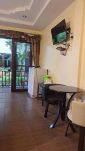 a living room with a table and a television on the wall at ปราณบุรีน้อยรีสอร์ท in Ban Nong Sua
