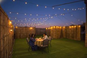 two people sitting at a table on a patio at night at FabHotel Infinity Stays Near Medanta- The Medicity, Gurgaon in Gurgaon