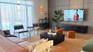 Una sala de estar con un sofá y un televisor de pantalla plana. en concrete villa, en Badīyah