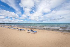 a row of lounge chairs on a beach at Beach 106 Direct Access Near Downtown Tart Trail in Traverse City