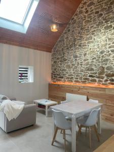 a room with a table and chairs and a stone wall at Maisonnette cosy proche de la côte in Lesneven