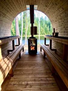 a fireplace in a room with two benches and a tunnel at Villa Renkaranta - Modern villa for 8-12 person, own beach, sauna & hot tub - surrounded by forests in Hämeenlinna