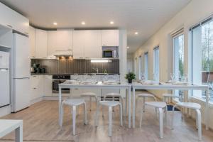 a kitchen with white cabinets and white stools at Villa Renkaranta - Modern villa for 8-12 person, own beach, sauna & hot tub - surrounded by forests in Hämeenlinna