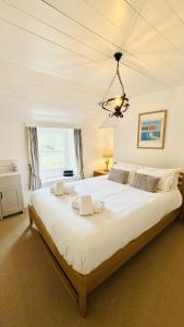 a bedroom with a large white bed with a chandelier at Waves End - Port Isaac Cornwall in Port Isaac