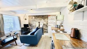 a living room with a blue couch and a stone wall at Waves End - Port Isaac Cornwall in Port Isaac