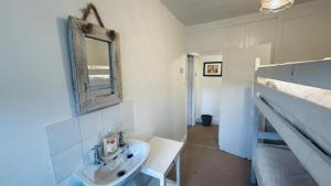a white bathroom with a sink and a mirror at Waves End - Port Isaac Cornwall in Port Isaac