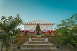 斋沙默尔haritage desert safari camp的院子里有一座带楼梯的白色帐篷