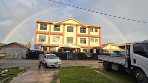 Una mujer parada frente a una casa con un arcoíris. en Zaru Hotel, en Gizo