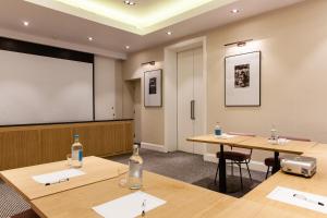 a classroom with two tables and a projection screen at The Rockwell in London