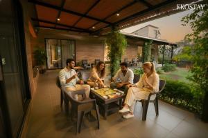 Casa Vayu 3 BHK - EKOSTAY في لونافالا: مجموعة من الناس يجلسون حول طاولة يلعبون