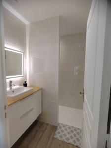 ein weißes Badezimmer mit Waschbecken und Spiegel in der Unterkunft L'Atelier T2 entièrement rénover in Gémozac