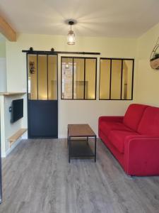 ein Wohnzimmer mit einem roten Sofa und einem Tisch in der Unterkunft L'Atelier T2 entièrement rénover in Gémozac