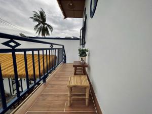 a balcony with a bench and a palm tree at Doc Bien Homestay Mui Ne - Entire Home in Ấp Khánh Phước (1)