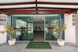 an entrance to a building with two potted plants at Seu apê de férias - Praia Grande in Praia Grande