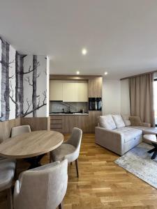 a living room with a table and a couch at BREATHE - Apartmani Zlatibor Centar in Zlatibor