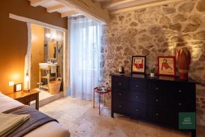 a bedroom with a dresser and a stone wall at L'Ecrin de Soligny in Soligny-les-Étangs
