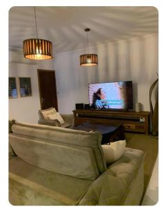 a living room with a couch and a flat screen tv at Casa de Praia in Bertioga