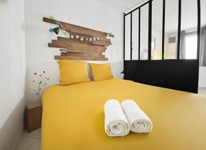 a bedroom with a yellow bed with towels on it at Studio calme, RER 5mn,Paris en 15mn,commerces 3mn in Nogent-sur-Marne