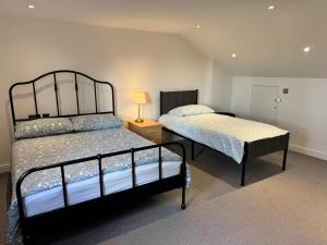 een slaapkamer met 2 bedden en een lamp op een nachtkastje bij Marigold Villa in Harrow