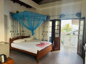 a bedroom with a bed with a blue canopy at Traveler's Cottage in Unawatuna