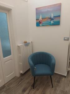 een blauwe stoel in een kamer met een schilderij aan de muur bij ACQUAMARINA - Home & Relax in Ascoli Satriano