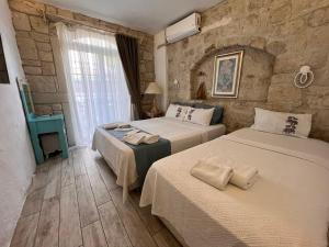 a bedroom with two beds and a stone wall at Alacati Asmali Konak Hotel in Alacati +95 photos