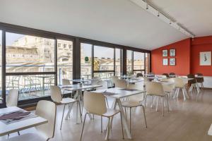 una sala da pranzo con tavoli, sedie e finestre di B&B Hotel Milano Aosta a Milano Altre 32 foto