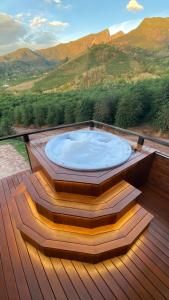 a hot tub on a deck with mountains in the background at Pousada Café da Mata in Alto Caparao