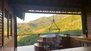 a hammock on a balcony with a view of a mountain at Pousada Café da Mata in Caparaó Velho