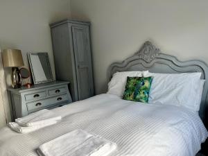 una camera con letto bianco, cassettiera e specchio di The Priory Cottage a Legbourne