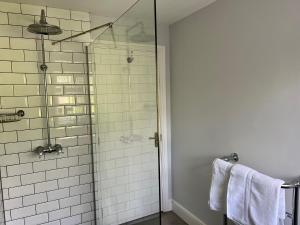 a bathroom with a glass shower with white tiles at The Priory Cottage in Legbourne +17 photos