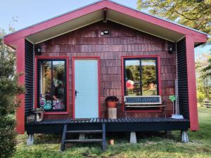 a tiny house with a red roof and a white door at Cabañas y Artesanías El Roble in Dalcahue