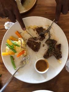 a plate of food with meat and vegetables on a table at Monaco Tangalle in Nikawatawana