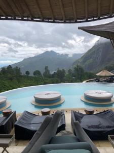 a swimming pool with chairs and mountains in the background at Monaco Tangalle in Nikawatawana
