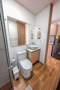a bathroom with a toilet and a sink and a mirror at Modern studio apartment with AC and secure parking in Acacías