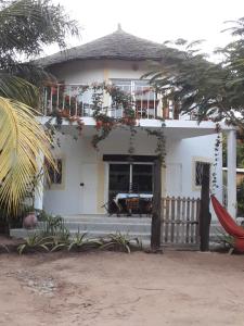 una casa bianca con un balcone sopra di Villa 150 mètres Océan a Cap Skirring