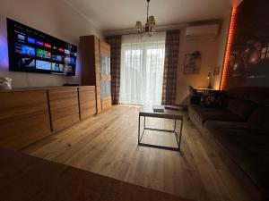 een woonkamer met een bank en een flatscreen-tv bij Apartament Dębowy Stół in Rzeszów