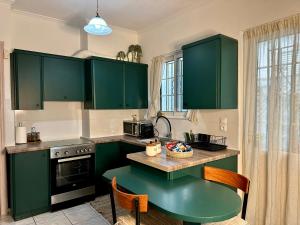 a kitchen with green cabinets and a table at Urban lodge Agios Dimitrios in Athens