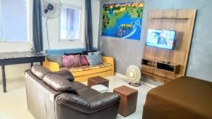 a living room with a couch and a tv at Chalé Ubatuba pertinho do mar in Ubatuba