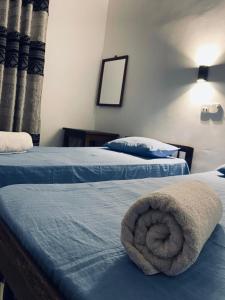 two beds with blue sheets and a towel on them at Chandra Holiday Home Hiriketiya in Dickwella