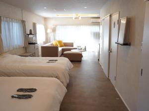 een hotelkamer met twee bedden en een bank bij スタイリッシュハウス博多 in Fukuoka