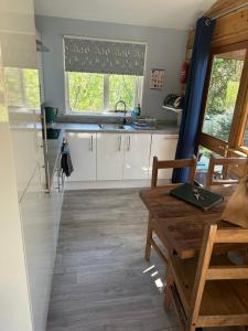 een keuken met witte kasten en een tafel en een raam bij Willow Valley in Bude