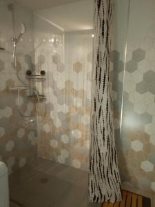 a shower with a black and white patterned shower curtain at Vielle-aure le 2bers 90 M2 avec mezzanine et linge inclu in Vielle-Aure